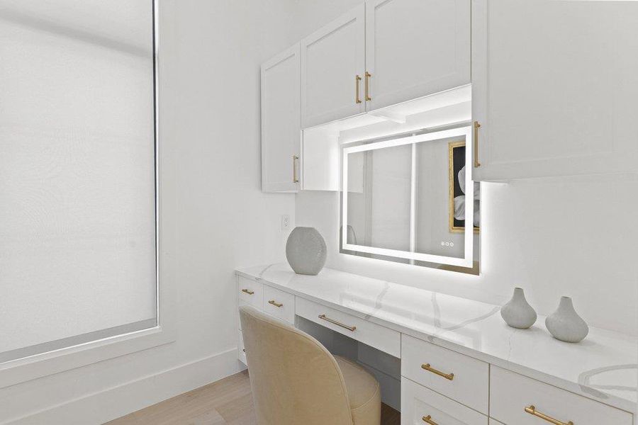 A well-lit vanity area offers abundant storage with sleek cabinetry and a radiant mirror.