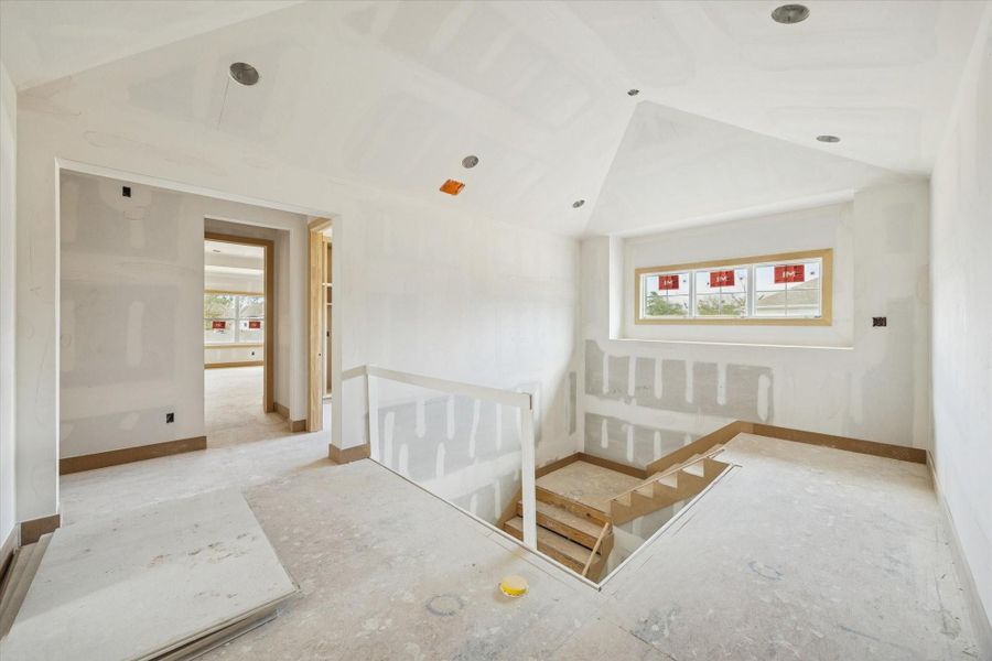 Light filled upper landing with vaulted ceiling detail and recessed lighting, creating an open transition to the game room and secondary bedrooms. Well placed window brings in natural light while maintaining privacy.