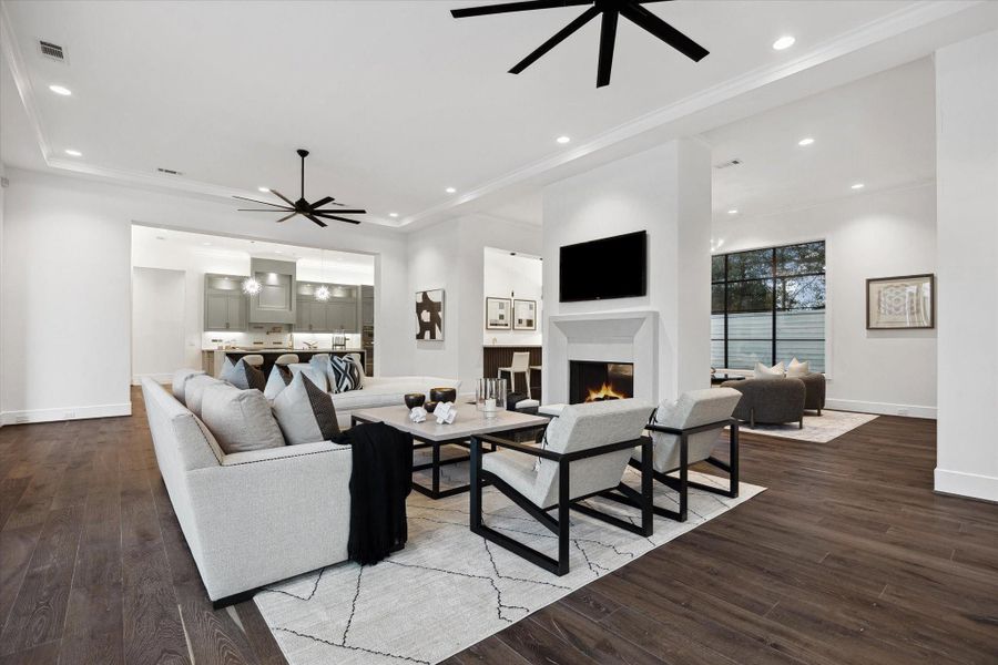 This view shows the large living room looking towards the kitchen. On the other side of the double sided fireplace is a wet bar, wine room and flexible space that could be used as another seating area. Great layout for entertaining!
