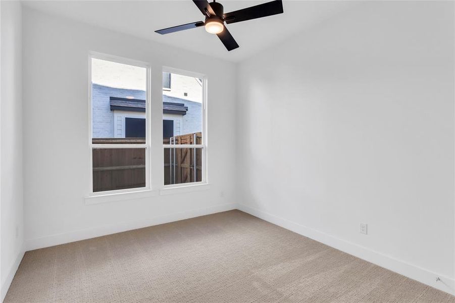 Spare room featuring light colored carpet and a ceiling fan