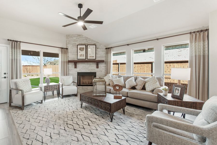 Living room with stone fireplace, ceiling fan, neutral seating, and patterned area rug