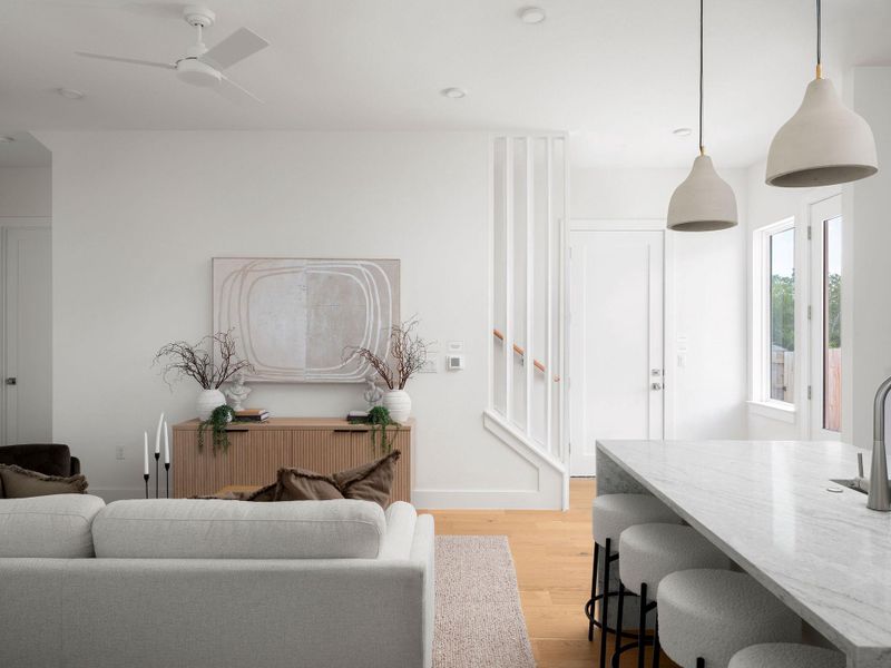 Natural light illuminates an open-concept living space with hardwood flooring and modern design.