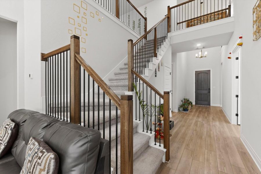 Foyer featuring wood finished floors, a chandelier, stairs, and a towering ceiling