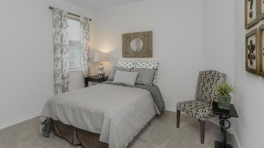Carpeted room featuring a single window with blinds and patterned curtains, light-toned walls, and white baseboards