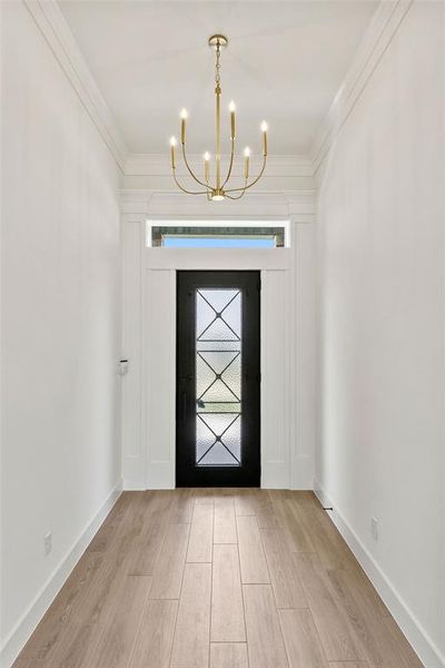 Foyer with light wood-style flooring, a chandelier, and ornamental molding Foyer with light wood-style flooring, a chandelier, and ornamental molding