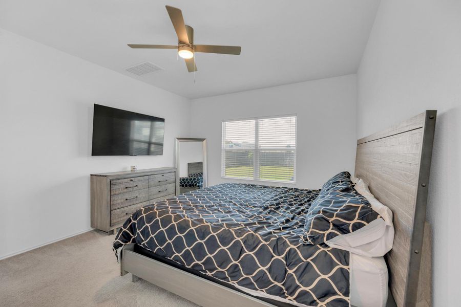 Carpeted bedroom with a ceiling fan and visible vents