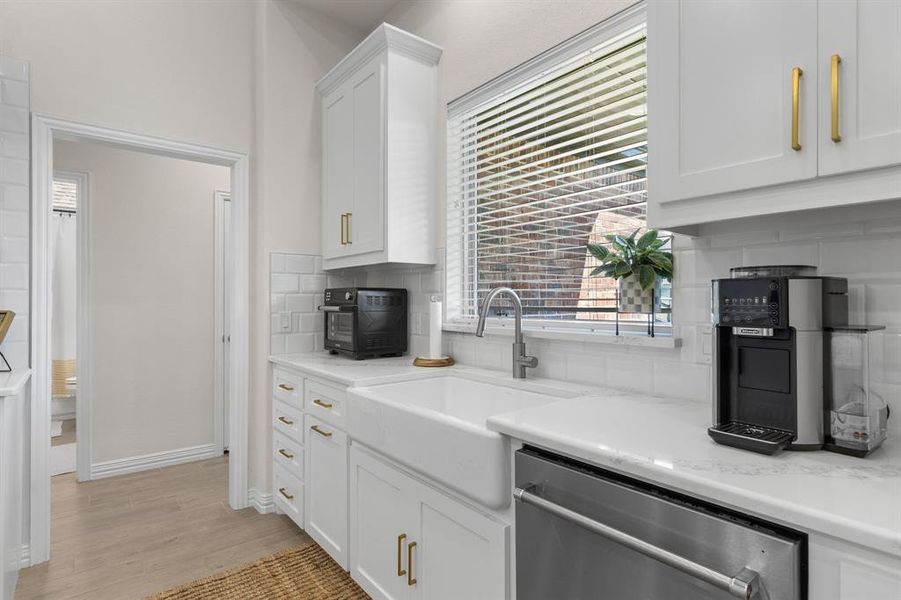 Kitchen featuring white cabinetry, dishwasher, tasteful backsplash, light wood-style flooring, and plenty of natural light Kitchen featuring white cabinetry, dishwasher, tasteful backsplash, light wood-style flooring, and plenty of natural light