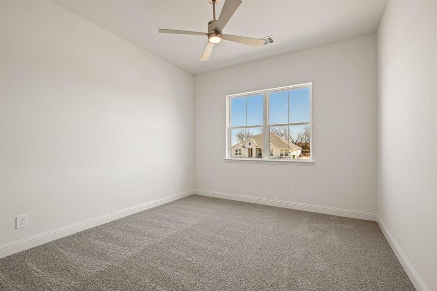 Carpeted empty room featuring ceiling fan, visible vents, and baseboards