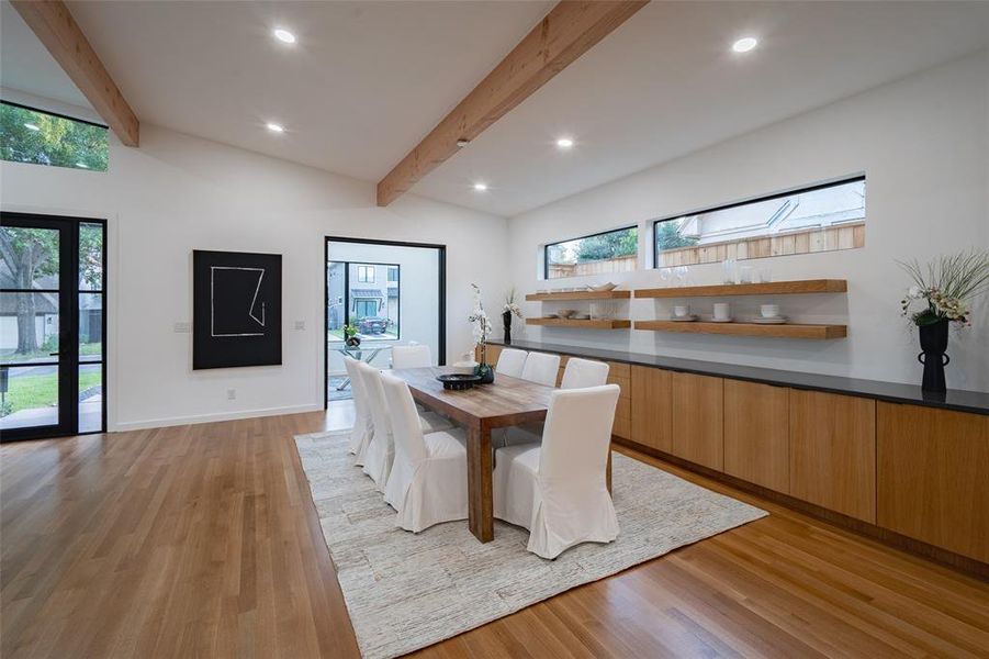 Dining space featuring a skylight, high vaulted ceiling, beamed ceiling, and light hardwood / wood-style flooring