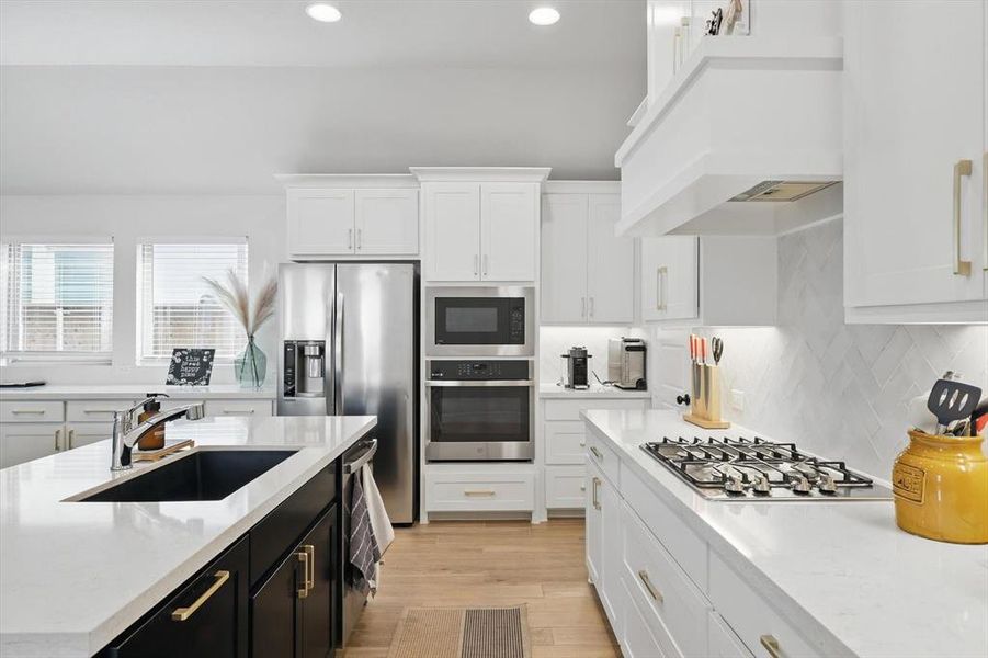 Kitchen with premium range hood, a sink, dark cabinetry, white cabinetry, and stainless steel appliances