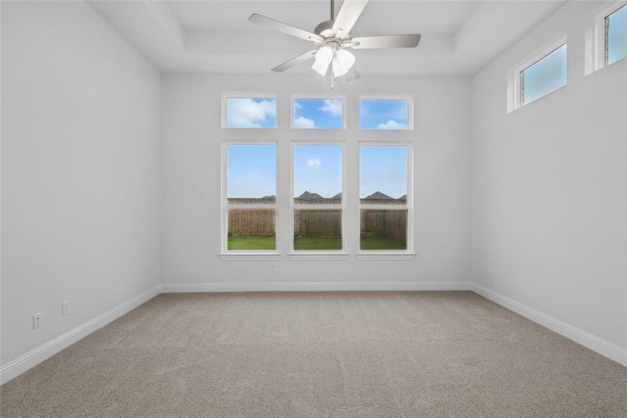 Empty room featuring carpet flooring, ceiling fan, and baseboards