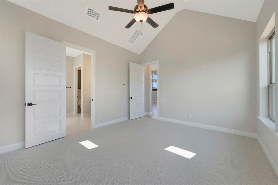 Unfurnished bedroom with light colored carpet, a high ceiling, and a ceiling fan Unfurnished bedroom with light colored carpet, a high ceiling, and a ceiling fan