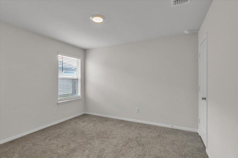 This room features carpeted flooring, a window with blinds, and light-colored walls