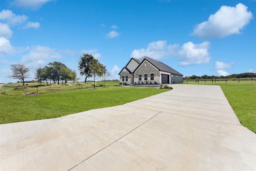 French country inspired facade with stone siding and concrete driveway French country inspired facade with stone siding and concrete driveway