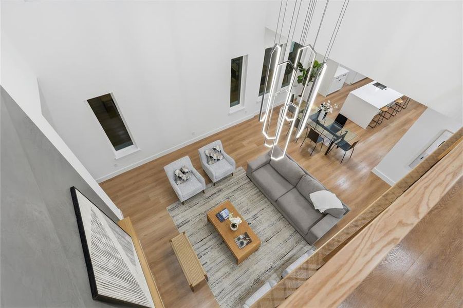 Double-height living space featuring wood-finish flooring, a contemporary linear chandelier, and recessed windows Double-height living space featuring wood-finish flooring, a contemporary linear chandelier, and recessed windows