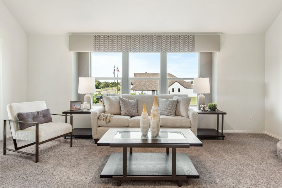 Living room with beige sofa, dark wood coffee table, and large window with neighborhood view