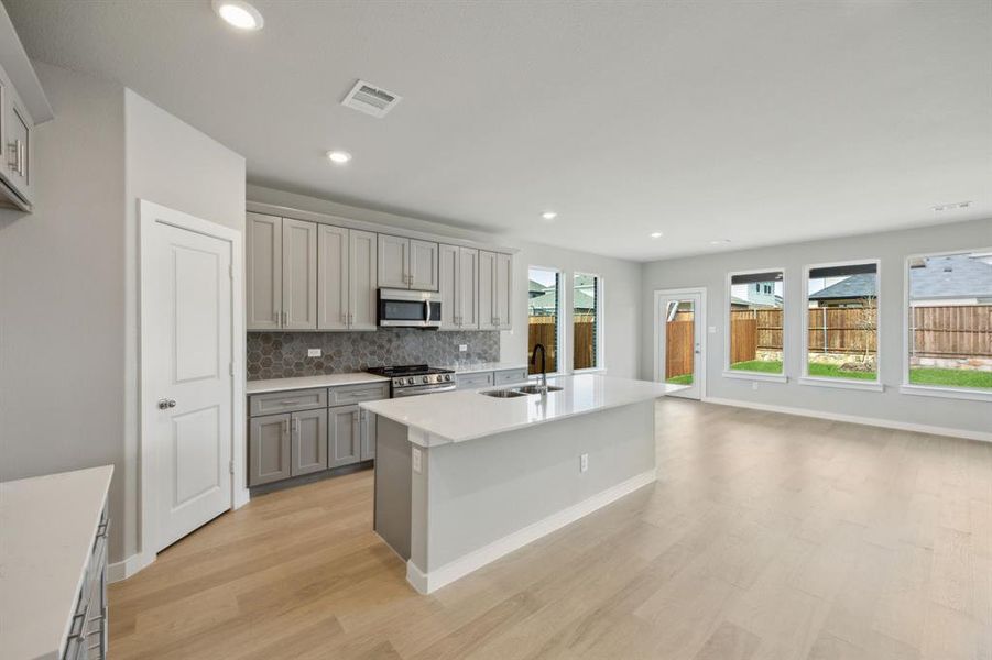 Kitchen with gray cabinets, decorative backsplash and stainless steel appliances