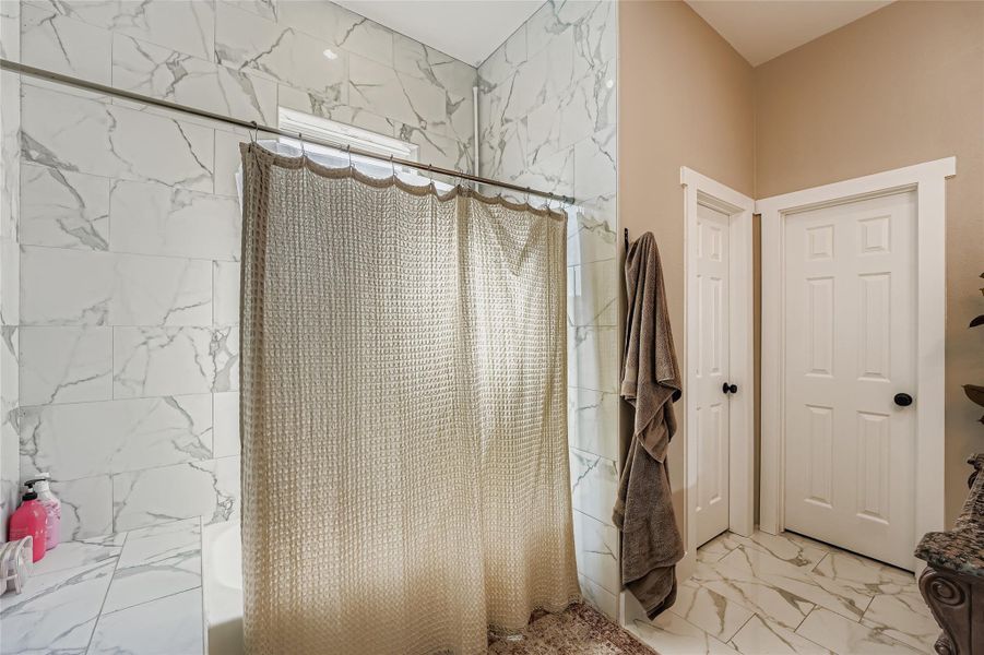 Bathroom with light marble finish floors and shower / tub combo Bathroom with light marble finish floors and shower / tub combo