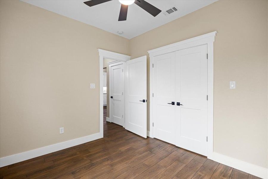 Unfurnished bedroom with dark wood finished floors, a closet, and a ceiling fan Unfurnished bedroom with dark wood finished floors, a closet, and a ceiling fan