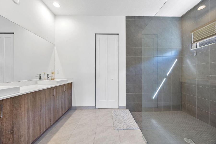 Bathroom with walk in shower, double vanity, recessed lighting, light tile patterned floors, and a closet