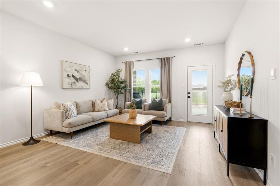 This bright living space features light wood-style flooring, recessed lighting, and a door providing exterior access This bright living space features light wood-style flooring, recessed lighting, and a door providing exterior access