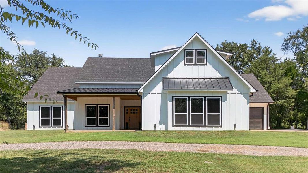Modern farmhouse style home with roof with shingles, a standing seam roof, a metal roof, and a front lawn Modern farmhouse style home with roof with shingles, a standing seam roof, a metal roof, and a front lawn