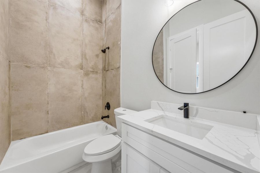 Stylish full bathroom with modern vanity, round mirror, sleek fixtures, and tiled tub/shower combo for a clean contemporary feel.