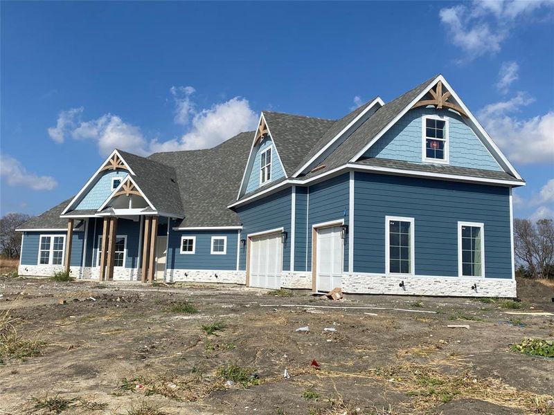 View of front of home featuring stone siding and a shingled roof View of front of home featuring stone siding and a shingled roof