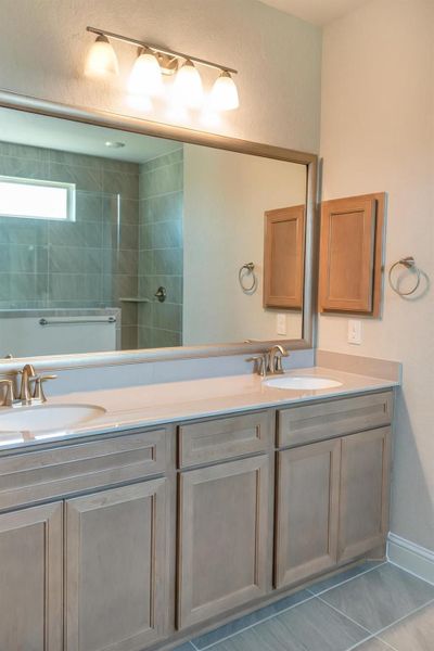 Bathroom with double vanity, light tile patterned flooring, and a walk in shower
