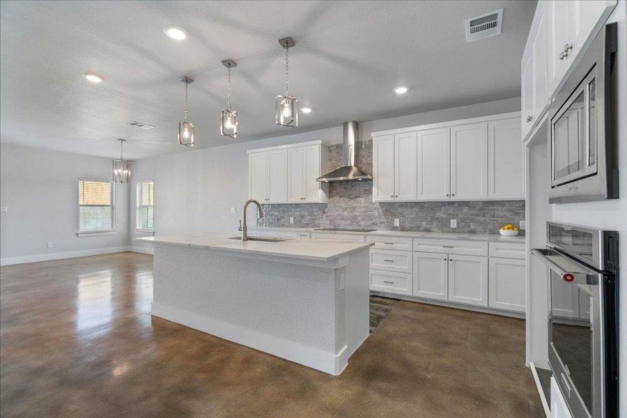 The kitchen includes a built-in microwave over oven, stainless steel appliances, and a lovely tile backsplash. The kitchen includes a built-in microwave over oven, stainless steel appliances, and a lovely tile backsplash.