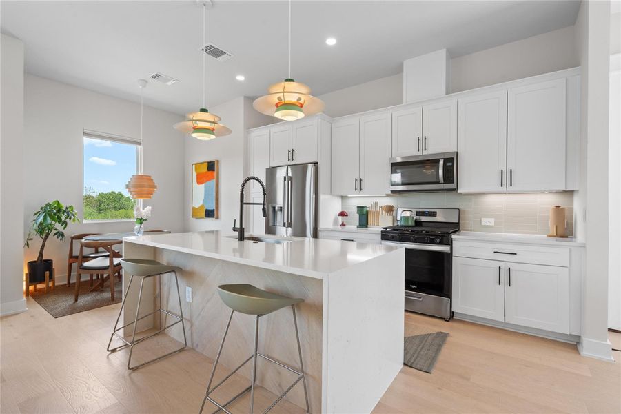 A well-lit kitchen with sleek white cabinetry and stainless steel appliances. A well-lit kitchen with sleek white cabinetry and stainless steel appliances.