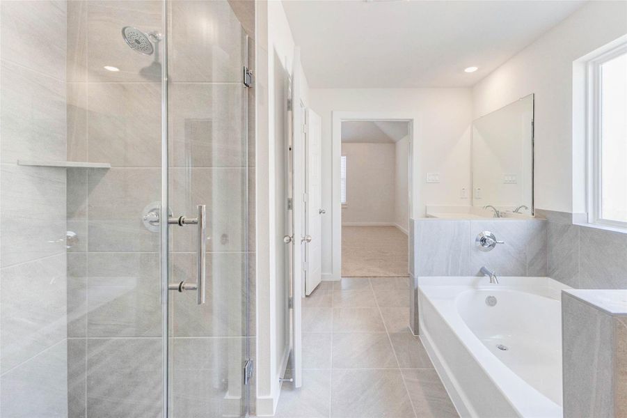 This striking ensuite features a glass-enclosed walk-in shower with designer tile, a relaxing soaking tub, and a seamless flow between functional and indulgent elements. The layout offers a luxurious start or end to your day. This striking ensuite features a glass-enclosed walk-in shower with designer tile, a relaxing soaking tub, and a seamless flow between functional and indulgent elements. The layout offers a luxurious start or end to your day.