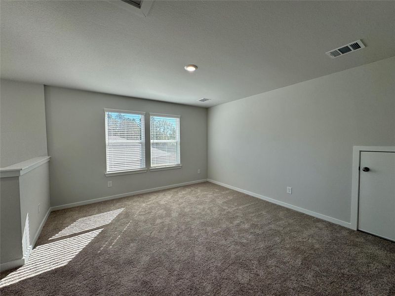Bright, carpeted upstairs game room featuring ample natural light from multiple windows, recessed lighting, and a neutral color palette. The open layout provides flexible use as a game room, media space, or secondary living area. Bright, carpeted upstairs game room featuring ample natural light from multiple windows, recessed lighting, and a neutral color palette. The open layout provides flexible use as a game room, media space, or secondary living area.