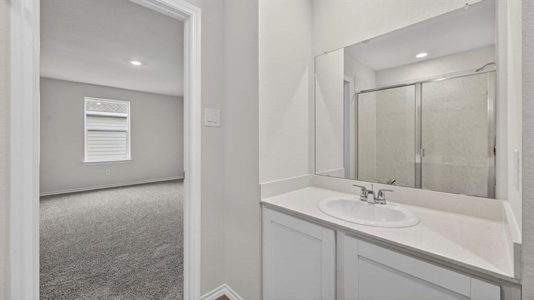 Bathroom vanity with a white countertop and integrated sink, chrome faucet, and expansive mirror