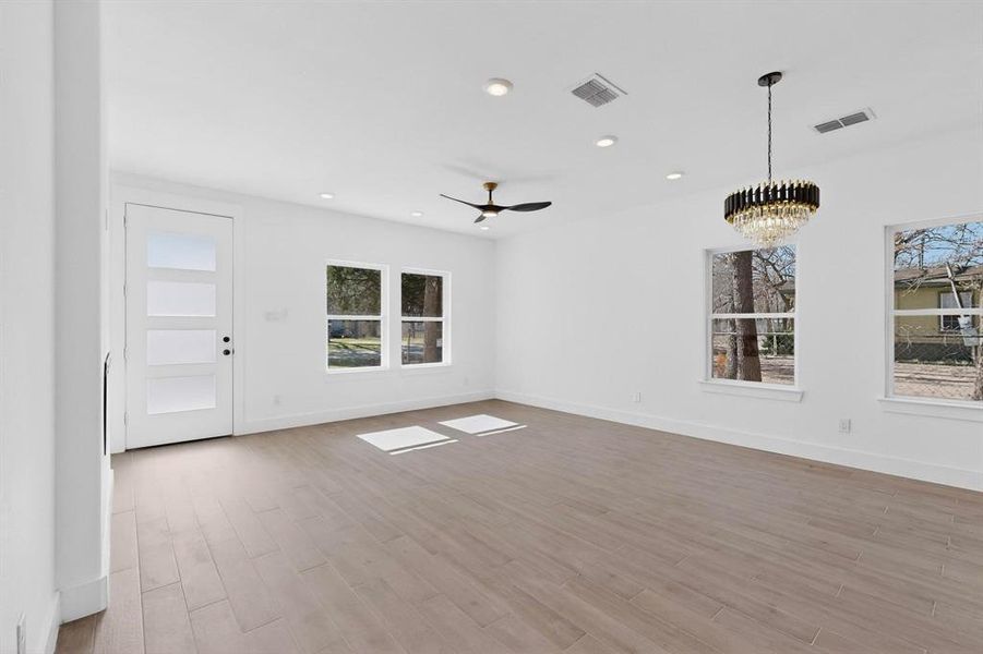 Spare room featuring light wood-type flooring, ceiling fan, recessed lighting, a chandelier, and healthy amount of natural light