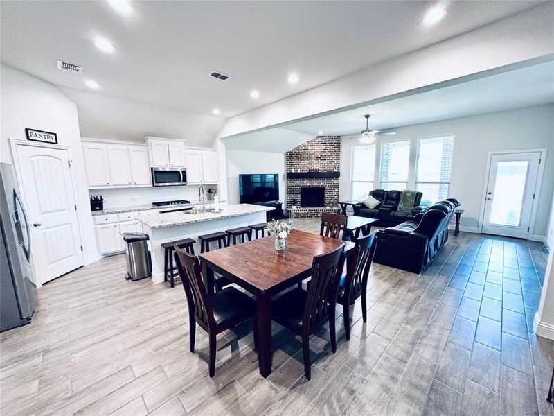 Dining area featuring light hardwood / wood-style flooring, sink, a brick fireplace, brick wall, and ceiling fan