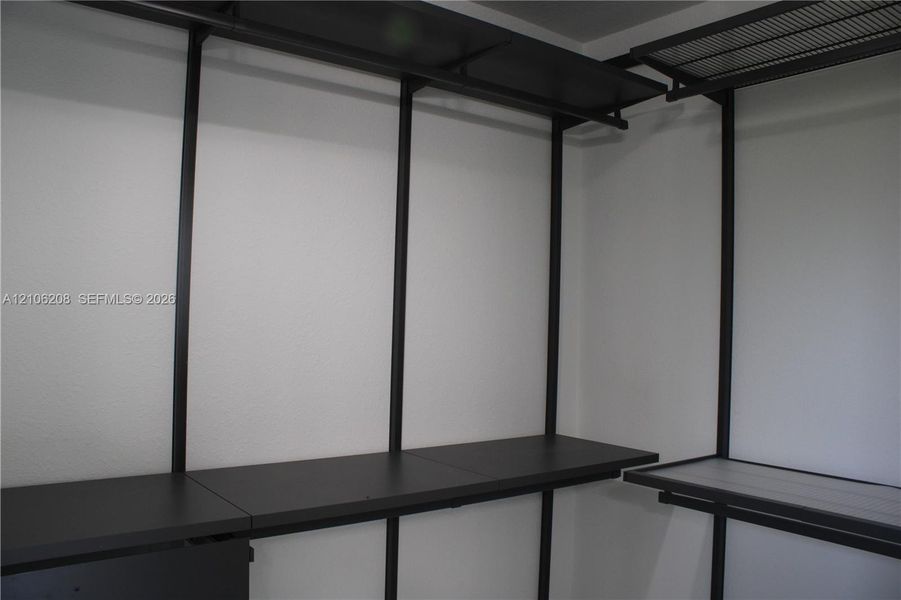Custom closet organization system featuring black metal framing, tiered shelving, and integrated hanging rods