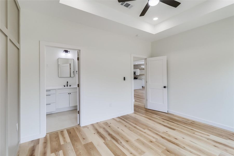 Unfurnished bedroom with recessed lighting,  connected bathroom, light wood-style floors, and baseboards