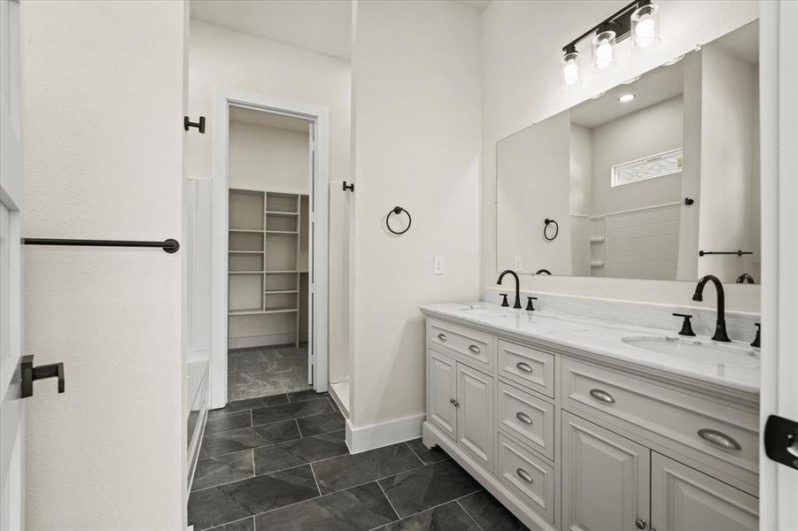 Full bathroom featuring double vanity and a spacious closet Full bathroom featuring double vanity and a spacious closet