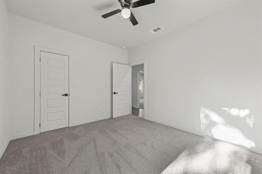 Carpeted empty room featuring ceiling fan