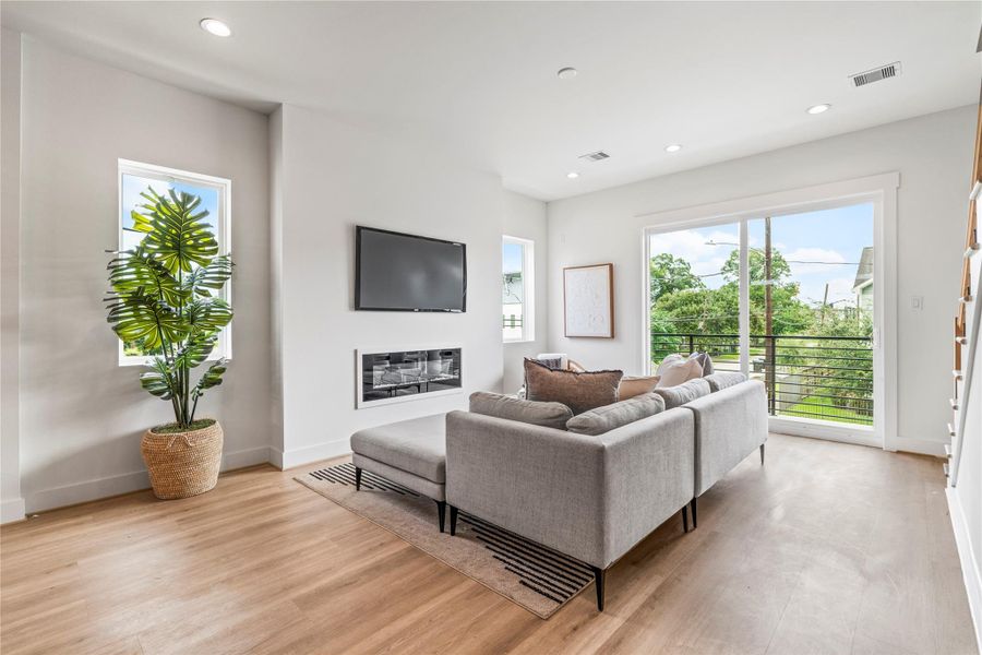 This living room has an electric fireplace for cozy nights in, custom windows that flood the space with natural light, and durable LVP flooring that runs throughout the home. This living room has an electric fireplace for cozy nights in, custom windows that flood the space with natural light, and durable LVP flooring that runs throughout the home.