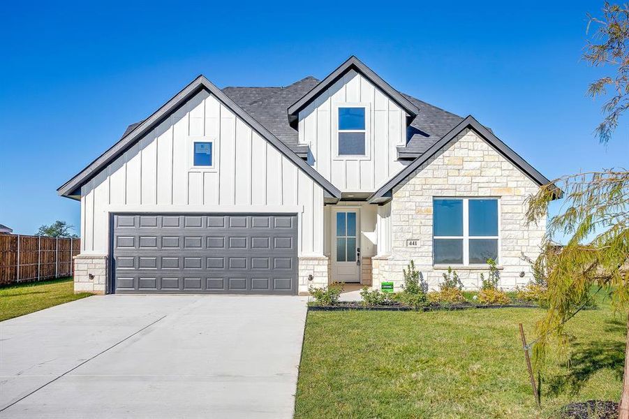 View of front of house featuring board and batten siding, driveway, a shingled roof, and stone siding