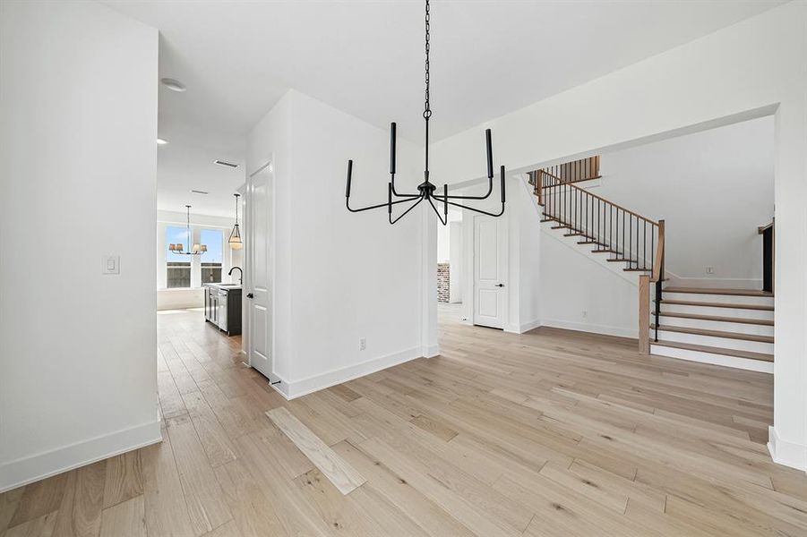 Unfurnished dining area featuring a chandelier, light wood finished floors, and stairway
