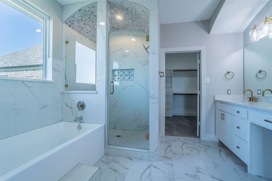 Bathroom featuring vanity, a bath, light marble finish floors, and a marble finish shower