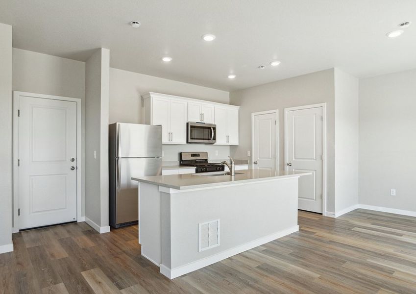 The kitchen has stainless steel appliances and plank flooring.