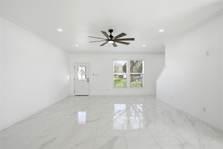Unfurnished living room with light marble finish floors, crown molding, recessed lighting, and ceiling fan Unfurnished living room with light marble finish floors, crown molding, recessed lighting, and ceiling fan