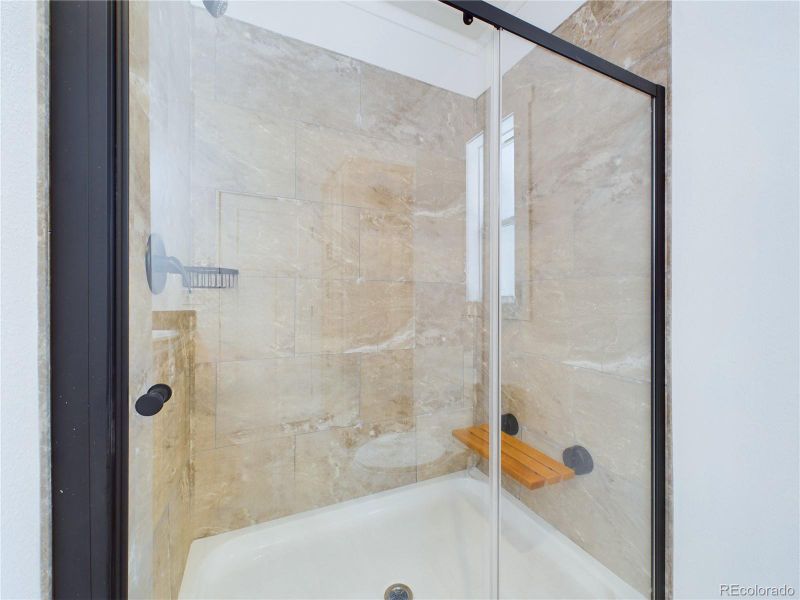 enclosed shower with glass door and fold down seat in shower