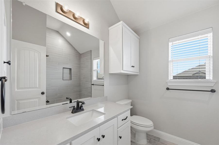 Full bath featuring vanity, vaulted ceiling, and a tile shower Full bath featuring vanity, vaulted ceiling, and a tile shower