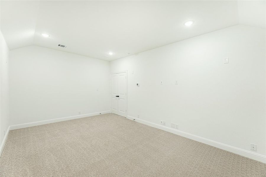 Empty room with white walls, beige carpet, recessed lighting, and a single white door