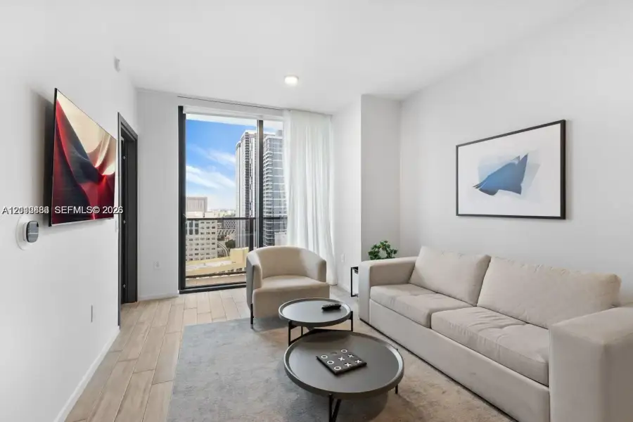 Floor-to-ceiling glass panel door, wood-finish flooring, recessed lighting, and a private balcony featuring urban scenery Floor-to-ceiling glass panel door, wood-finish flooring, recessed lighting, and a private balcony featuring urban scenery